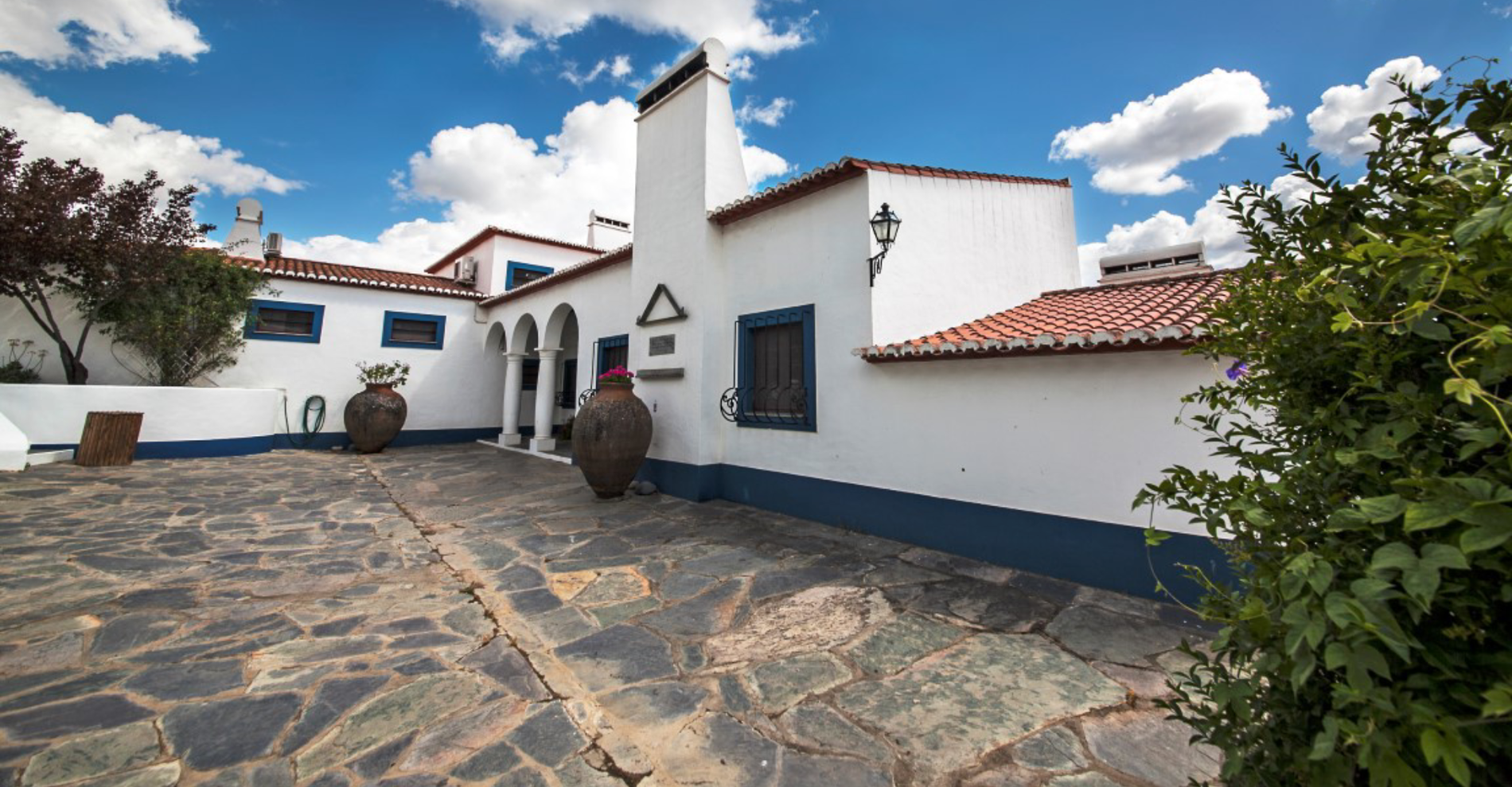 una mujer monta una bicicleta por una calle estrecha entre dos edificios blancos