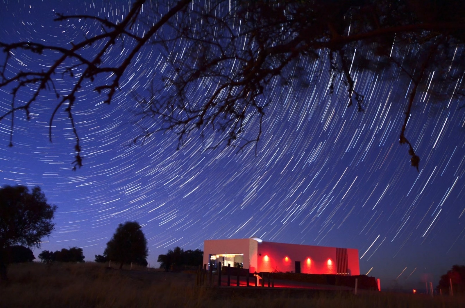 a starry night sky with a white building in the foreground