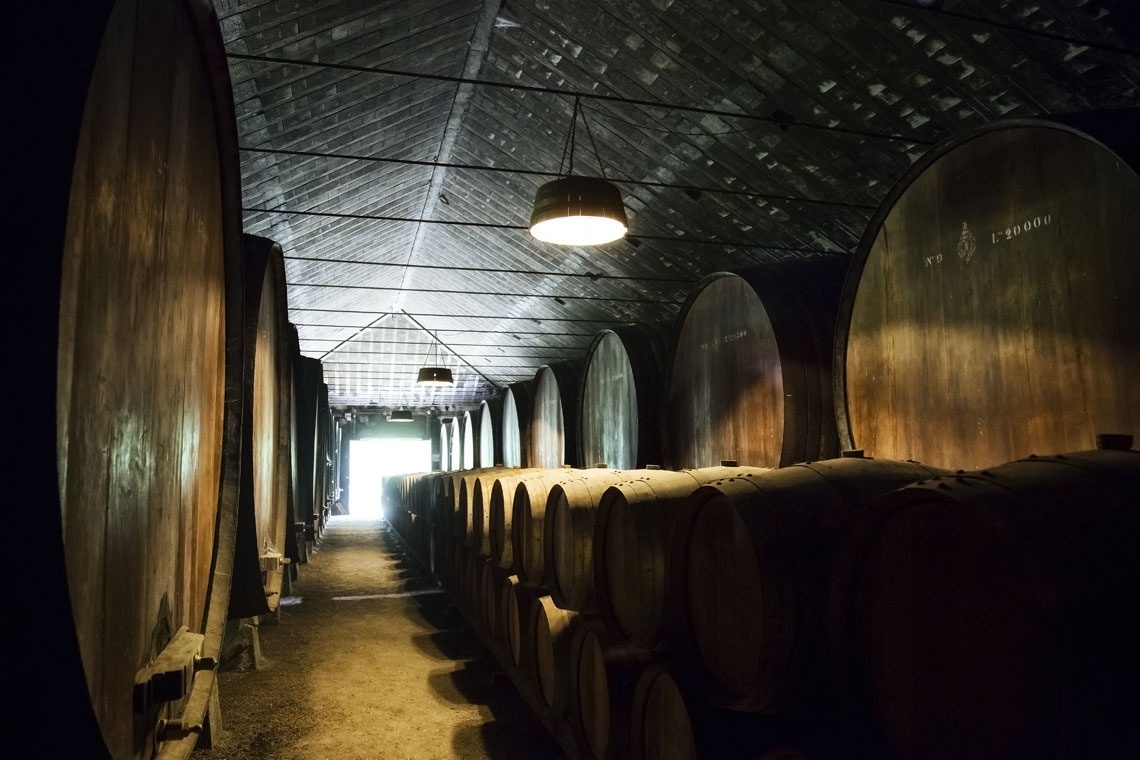 a row of barrels in a dark room with a light hanging from the ceiling