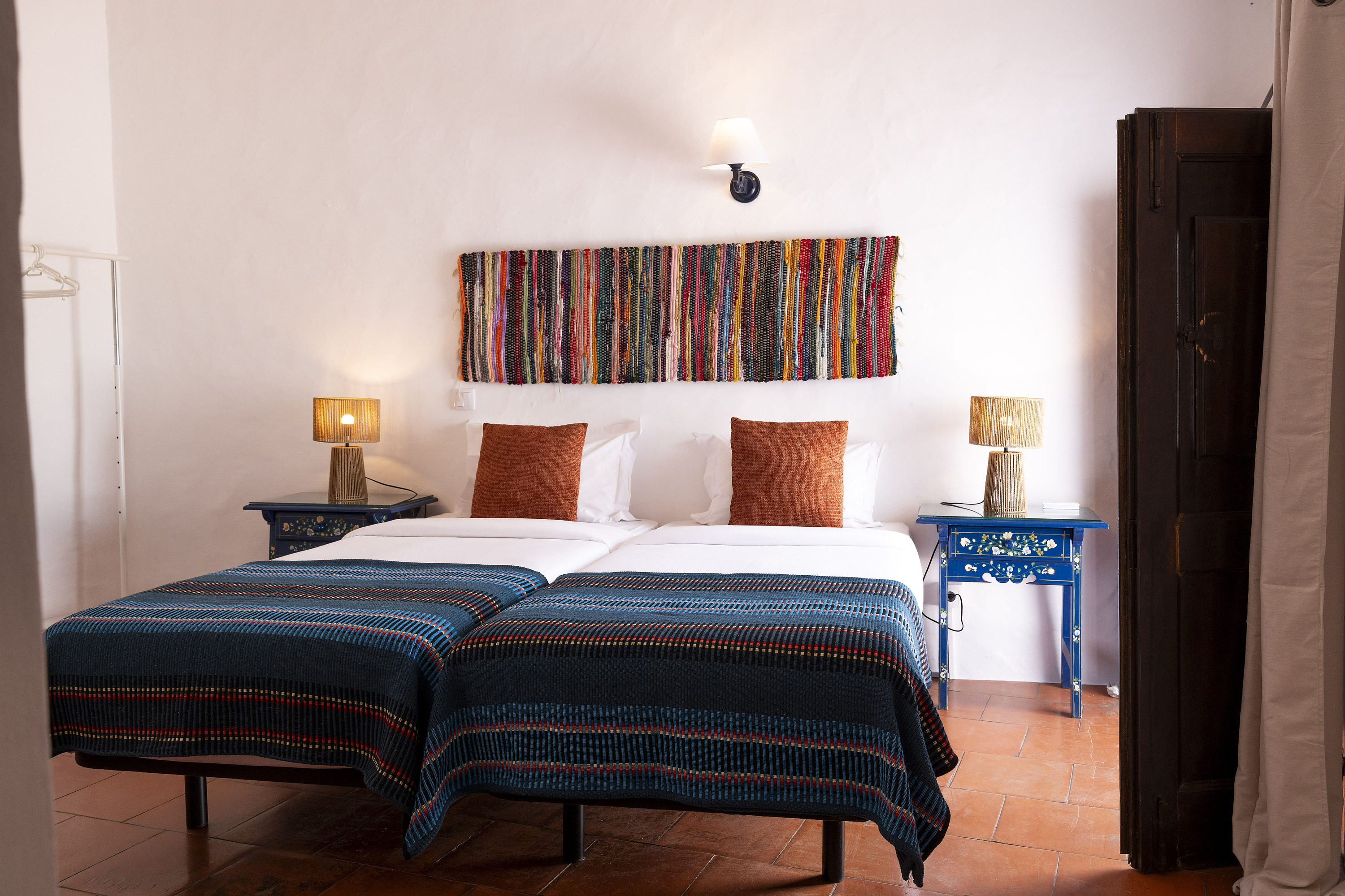 Two twin beds with blue and red striped blankets in a hotel room. Opening of Sítio da Moura Restaurant | Horta da Moura