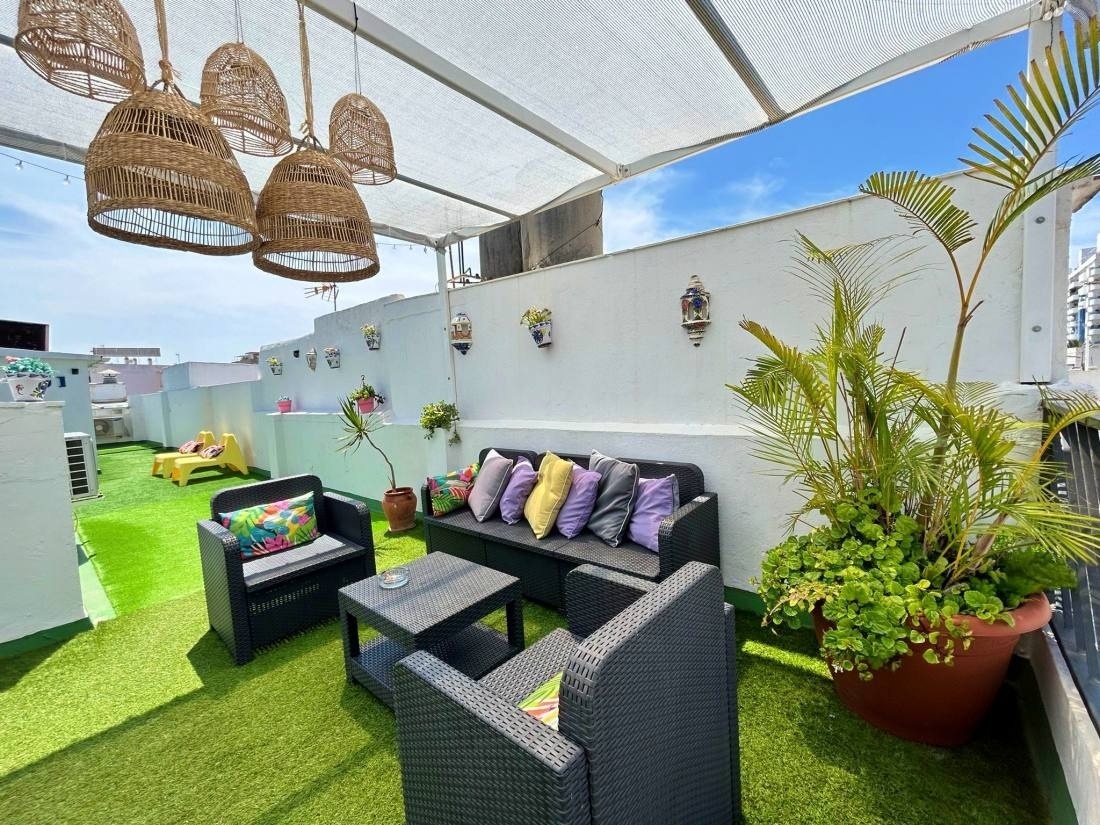 a patio with a couch and chairs with purple and yellow pillows