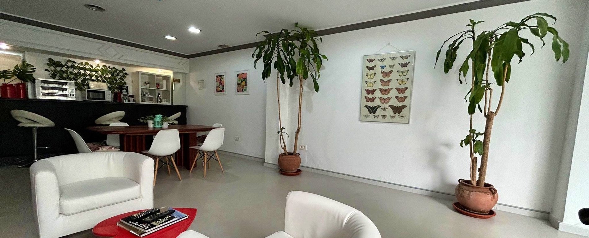una sala de estar con una mesa y sillas y un cartel de mariposas en la pared