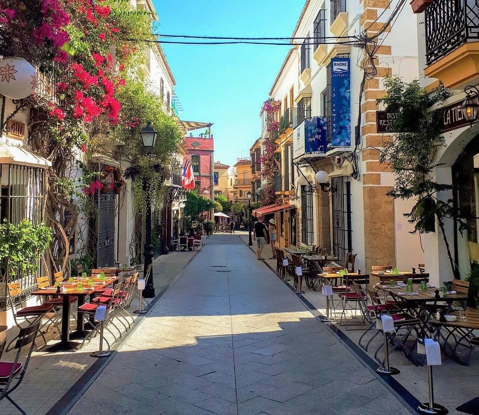 una calle llena de mesas y sillas con un cartel que dice la tiendita