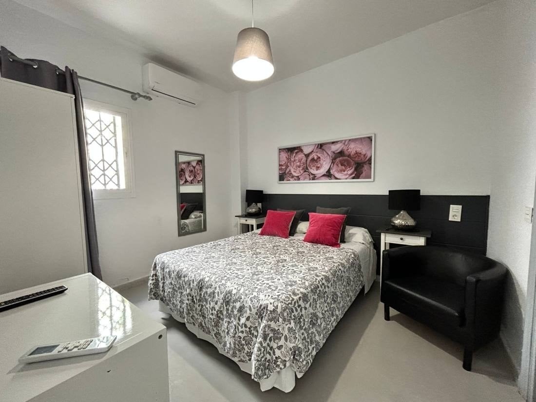 una habitación con una cama y una silla y un cuadro de rosas en la pared