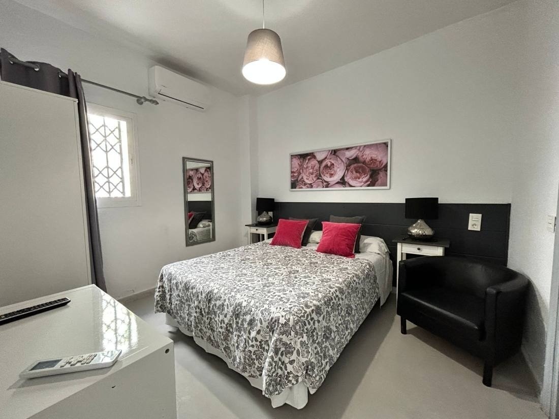 una habitación con una cama y una silla y un cuadro de rosas en la pared