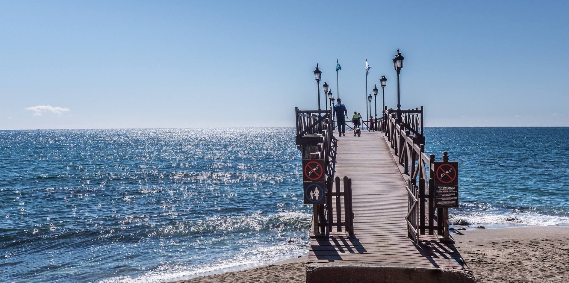 un hombre y un niño caminan por un muelle de madera en el océano