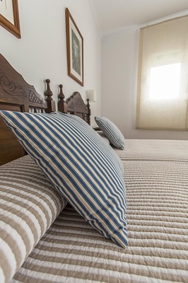 a bed with a blue and white striped pillow on it