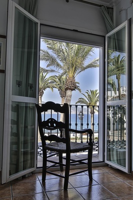una silla está sentada frente a una ventana con palmeras en el fondo
