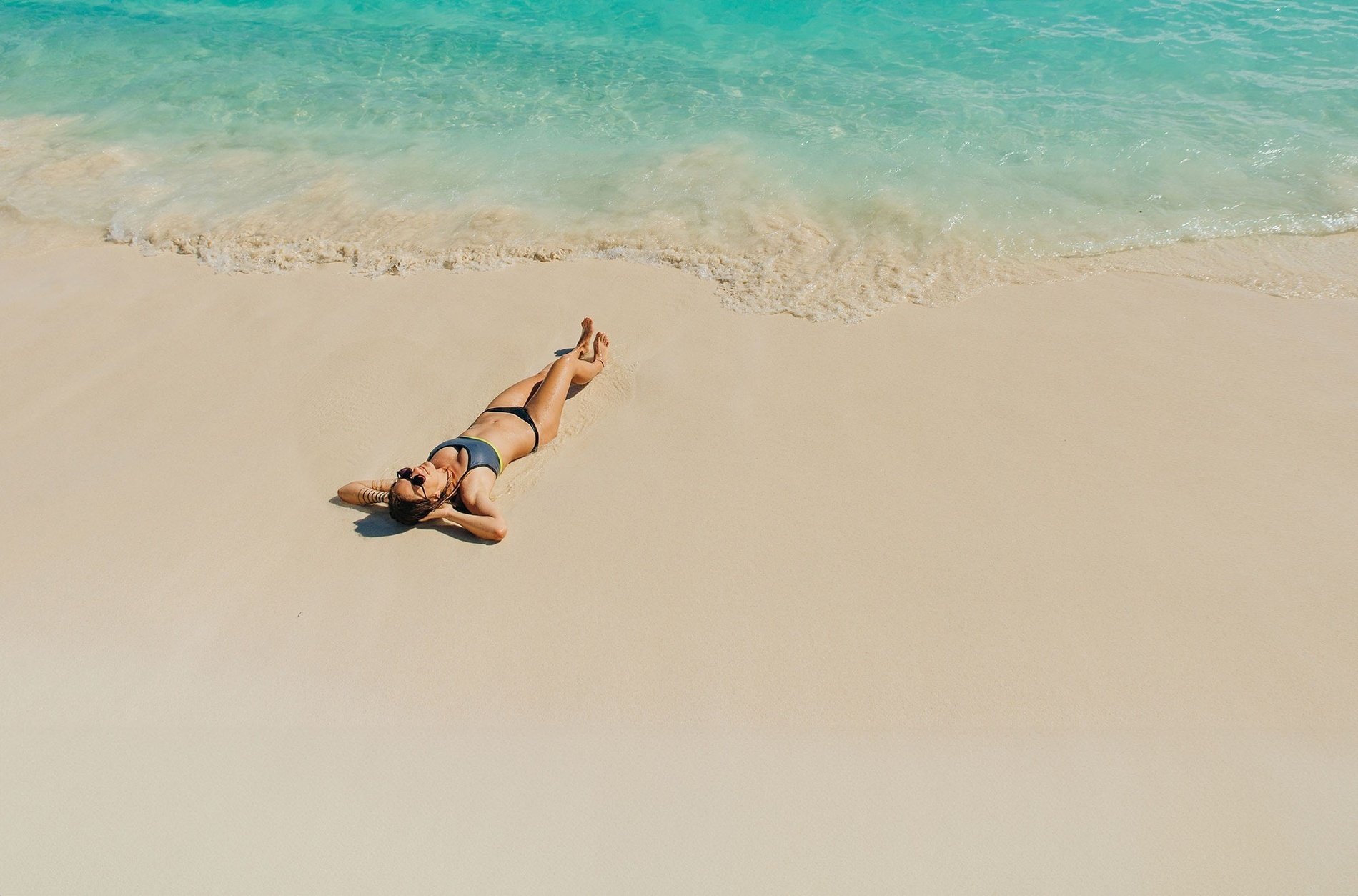 una mujer en bikini está acostada en la playa