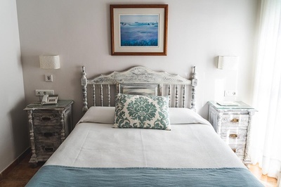 a bed with a blue and white pillow and a picture above it