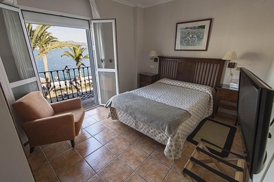 a bedroom with a large bed and a balcony overlooking the ocean