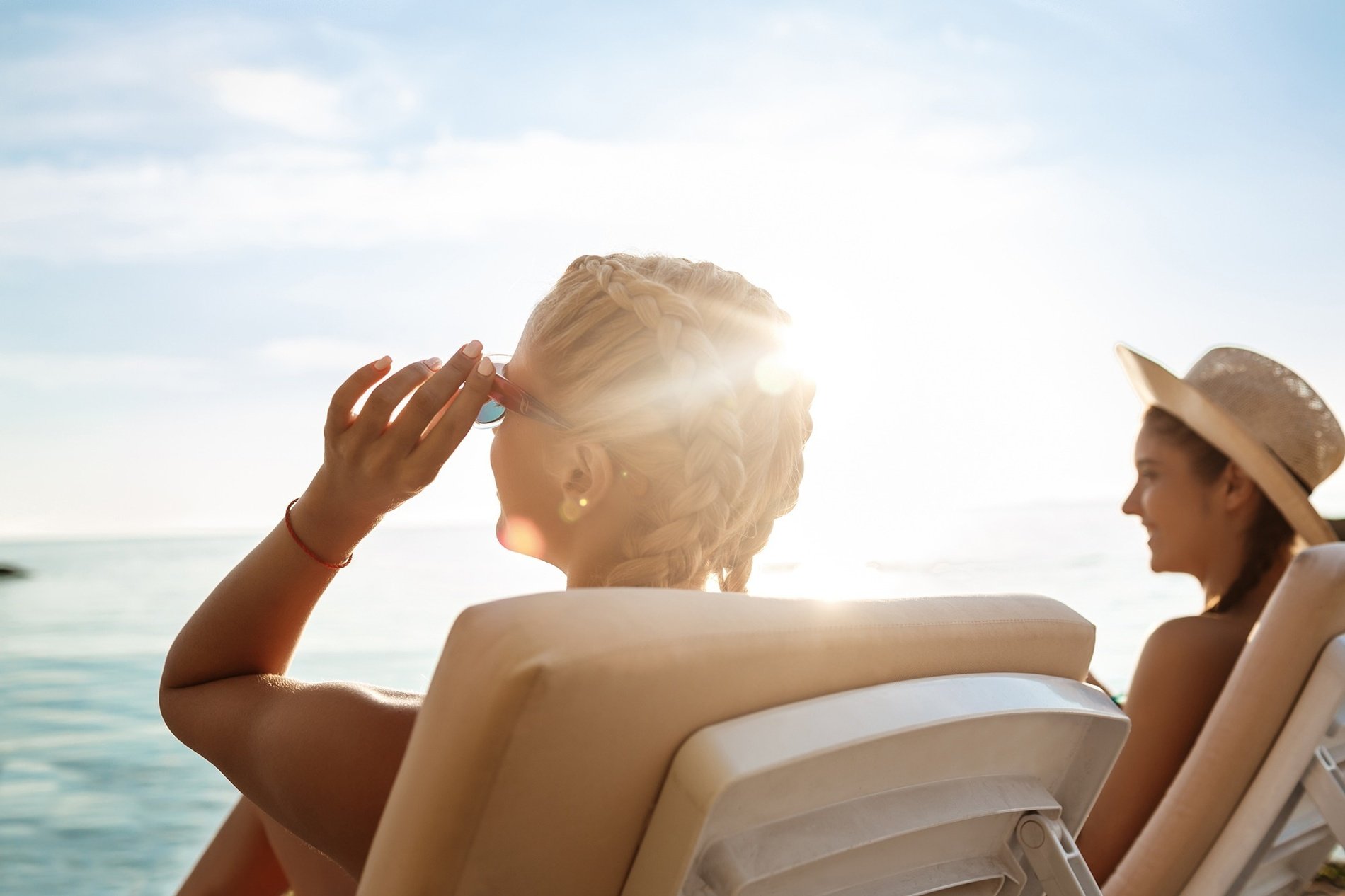 dos mujeres están sentadas en sillas de playa mirando el sol