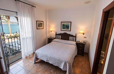 a bedroom with a bed and a balcony overlooking the ocean