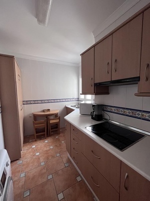 una cocina con gabinetes de madera y una mesa y sillas