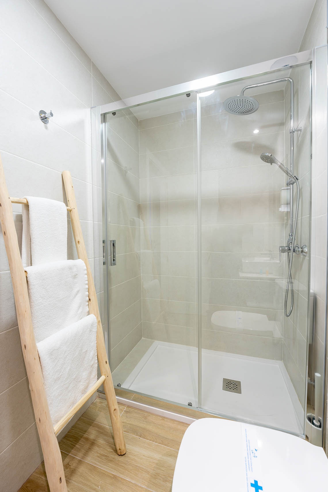 un baño con una escalera de madera y una ducha de vidrio