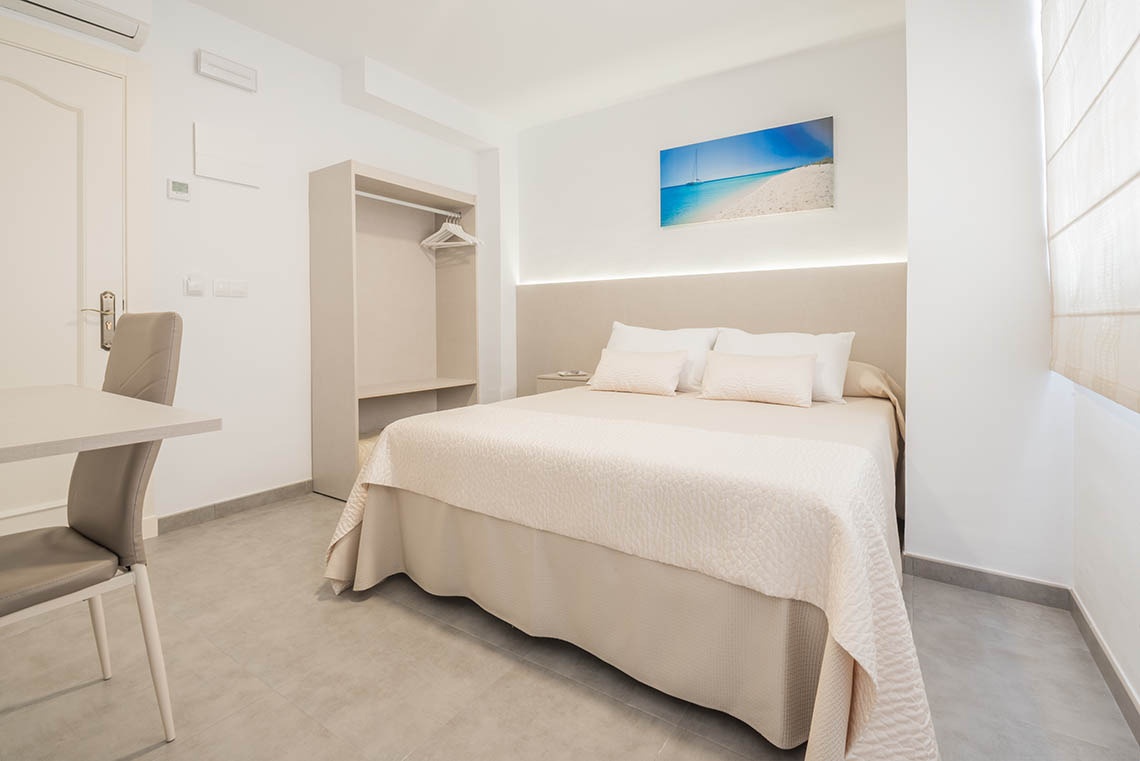 una habitación con una cama y una pintura de una playa en la pared