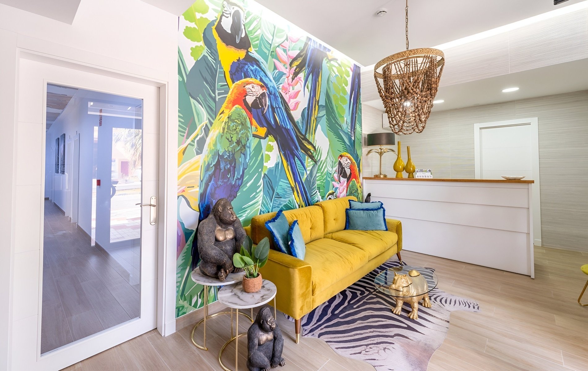 una sala de estar con un sofá amarillo y un mural de pájaros en la pared