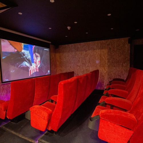 a movie theater with red seats and a projector screen