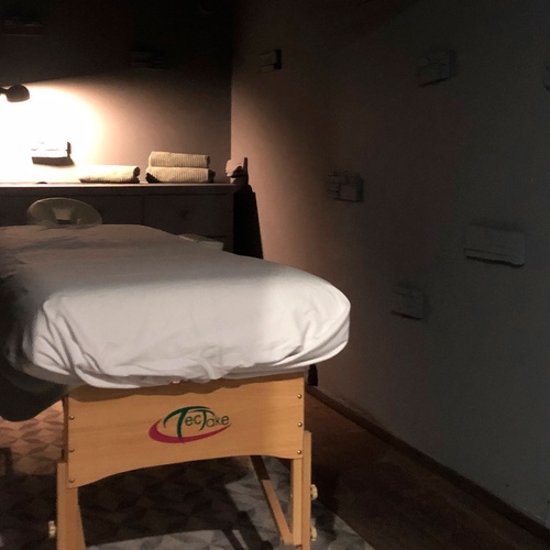 una habitación oscura con una mesa de masaje y una lámpara