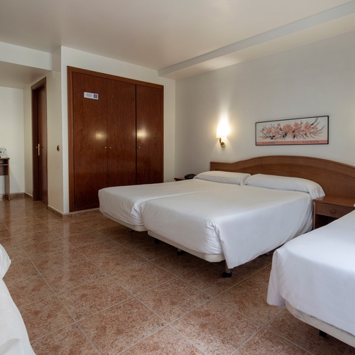 una habitación de hotel con tres camas y un escritorio
