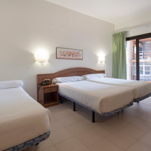 una habitación con tres camas y una pintura en la pared