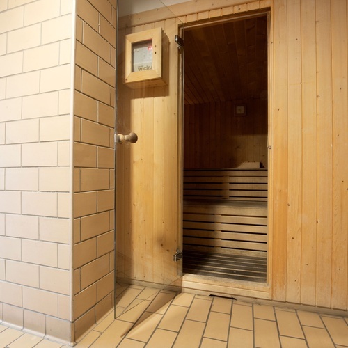 a wooden sauna with the door open and a box that says ' bosch ' on it