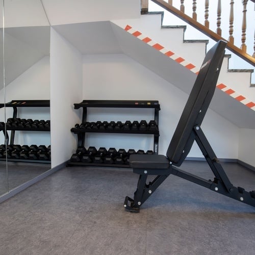 a gym with a bench and a rack of dumbbells