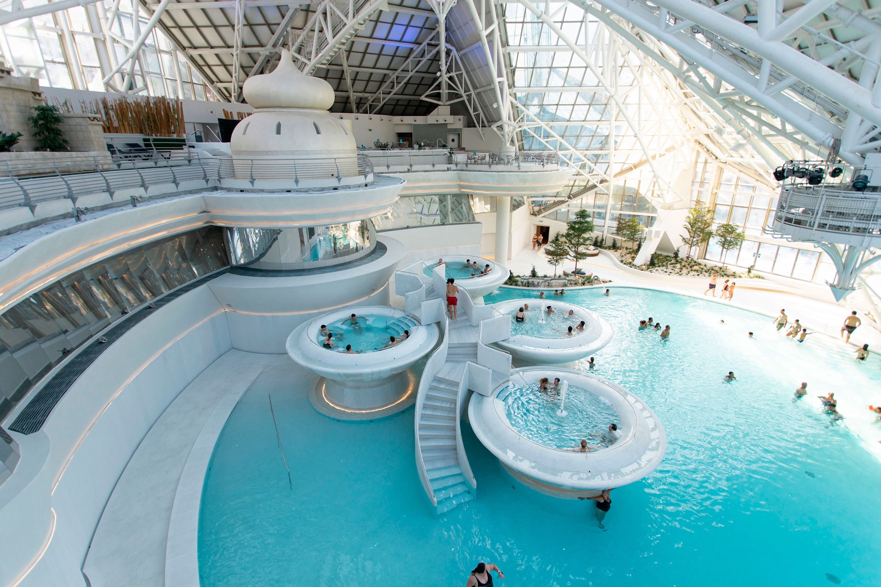 un grupo de personas nadando en una piscina con escaleras y toboganes