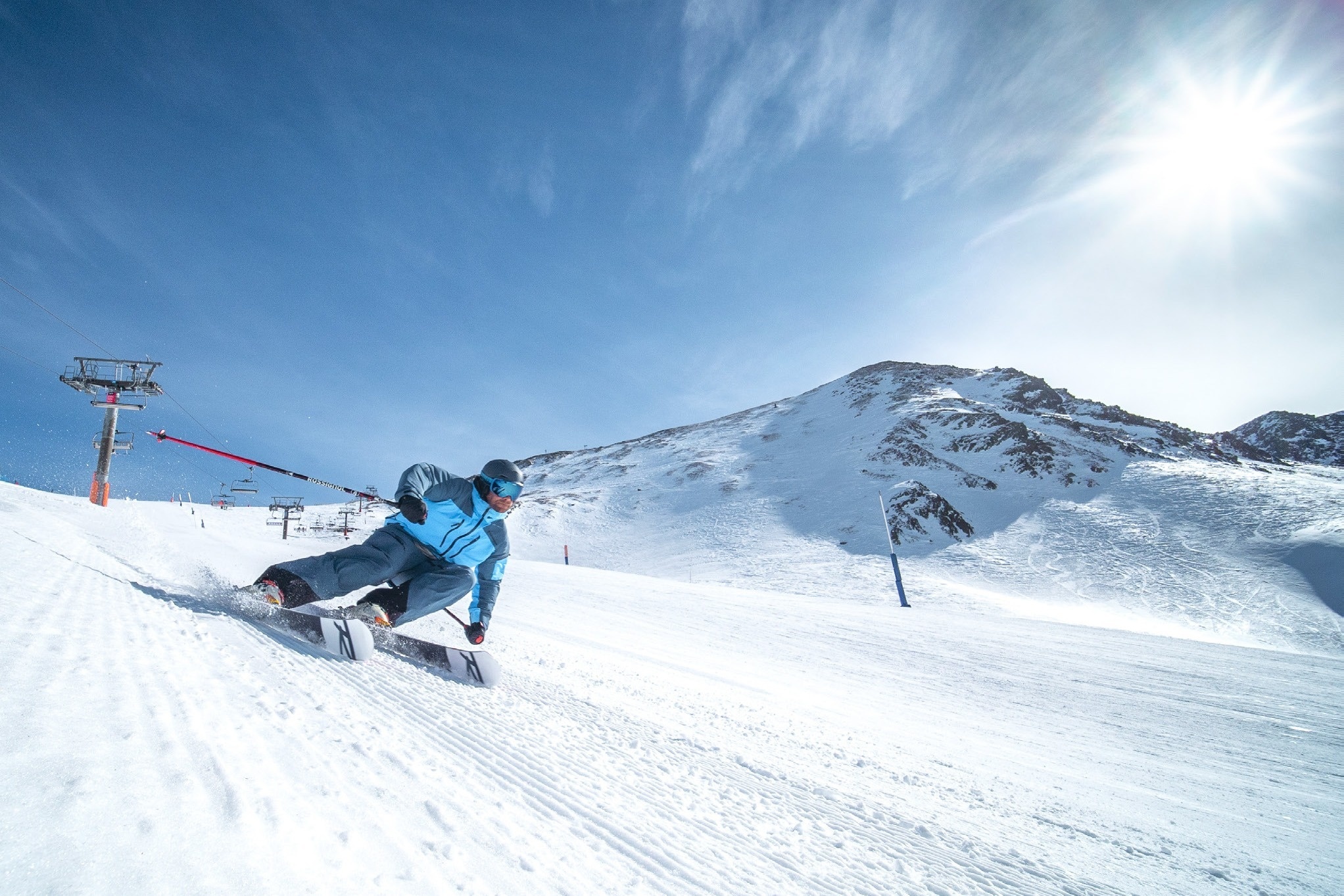 un hombre con una chaqueta azul y pantalones negros es esquiando por una ladera cubierta de nieve