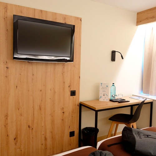 a hotel room with a tv on the wall and a desk