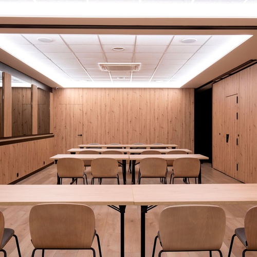 une salle de conférence avec des tables et des chaises en bois