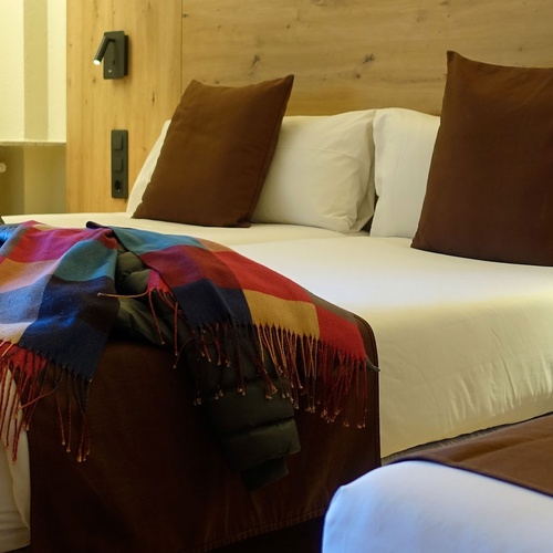 un lit avec une couverture colorée et des oreillers bruns