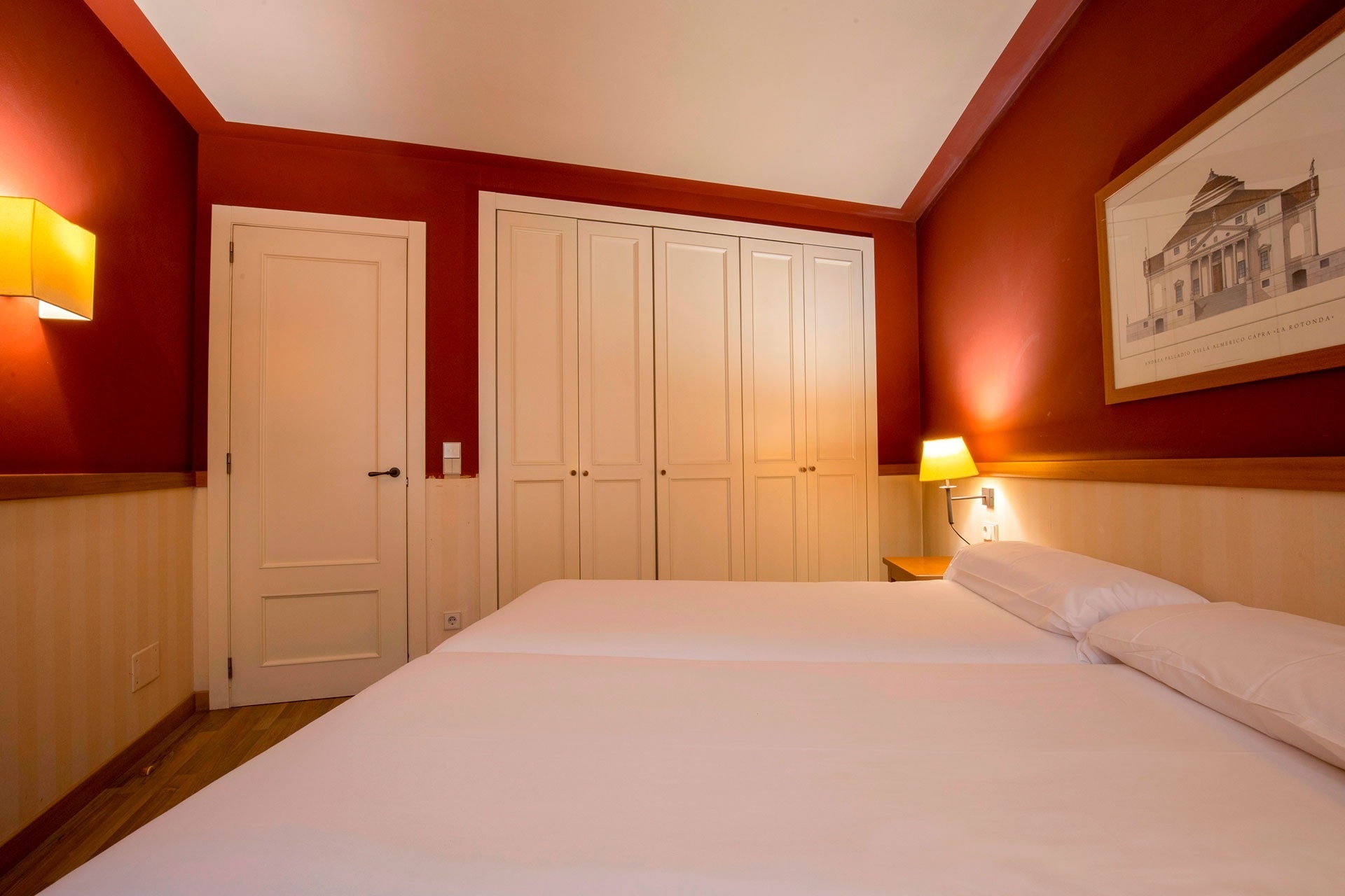 a bedroom with two beds and a picture of a building on the wall