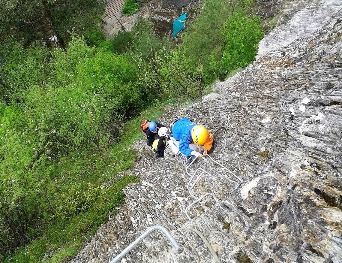 deux personnes escaladent une paroi rocheuse avec une échelle métallique