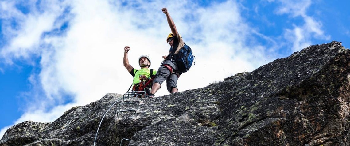 deux hommes debout au sommet d' une montagne avec leurs bras en l' air