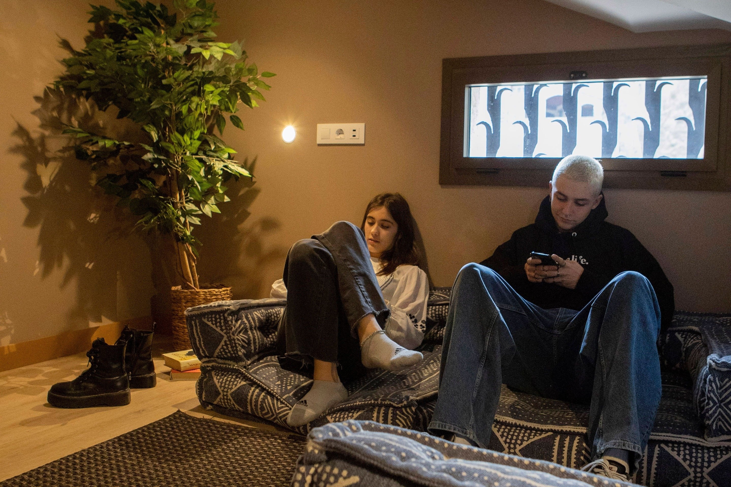 un homme et une femme sont assis sur un canapé et regardent leurs téléphones