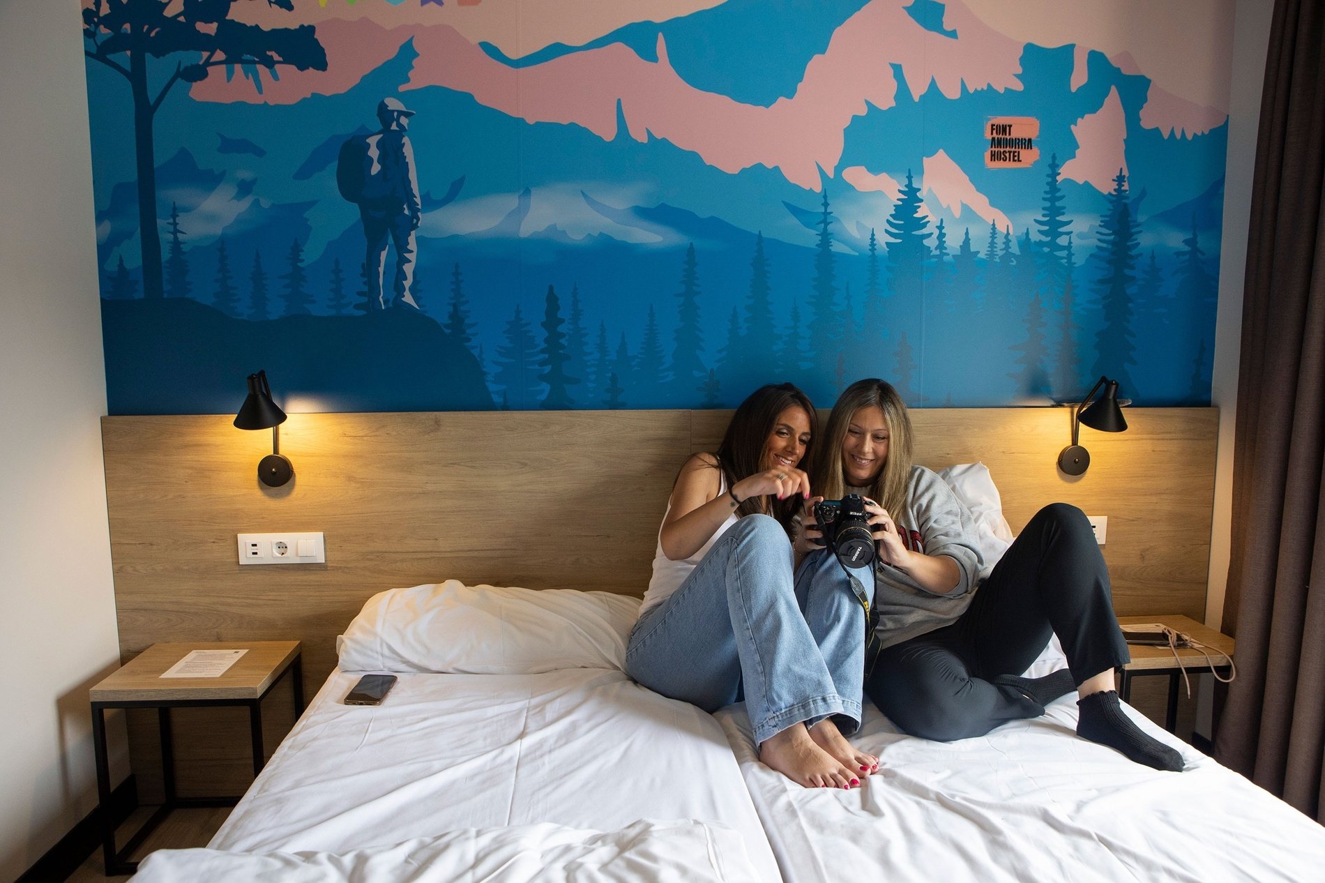 two women sitting on a bed with a sign that says first class hotel