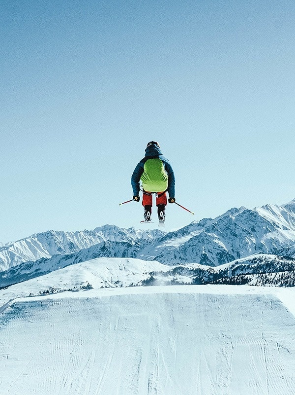 un skieur saute en l' air avec des montagnes en arrière-plan