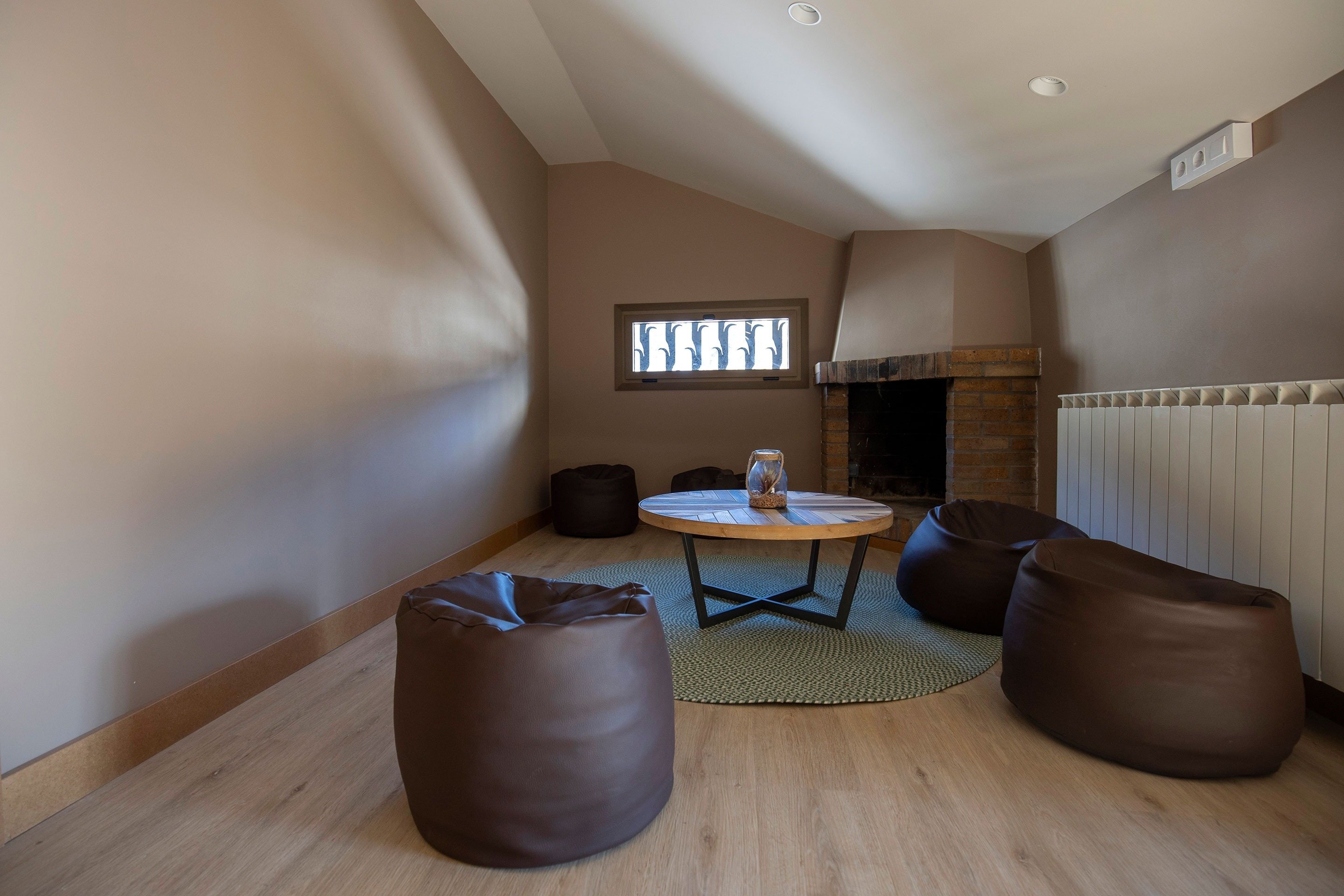 une salle avec une table et des poufs et une cheminée