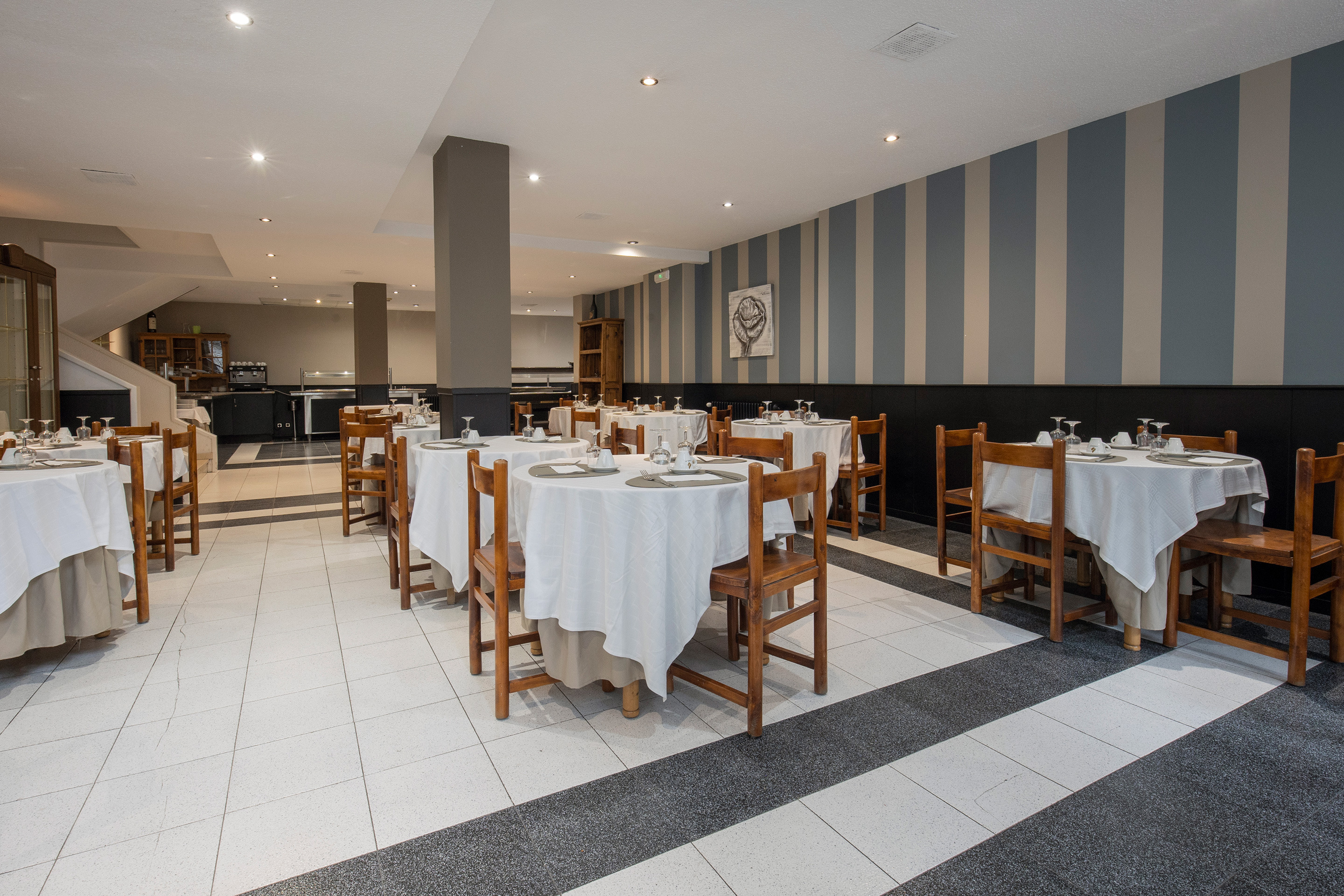 Restaurante del hotel con mesas puestas y sillas de madera. Ideal para tu próximo NEXTA: Corporativa.