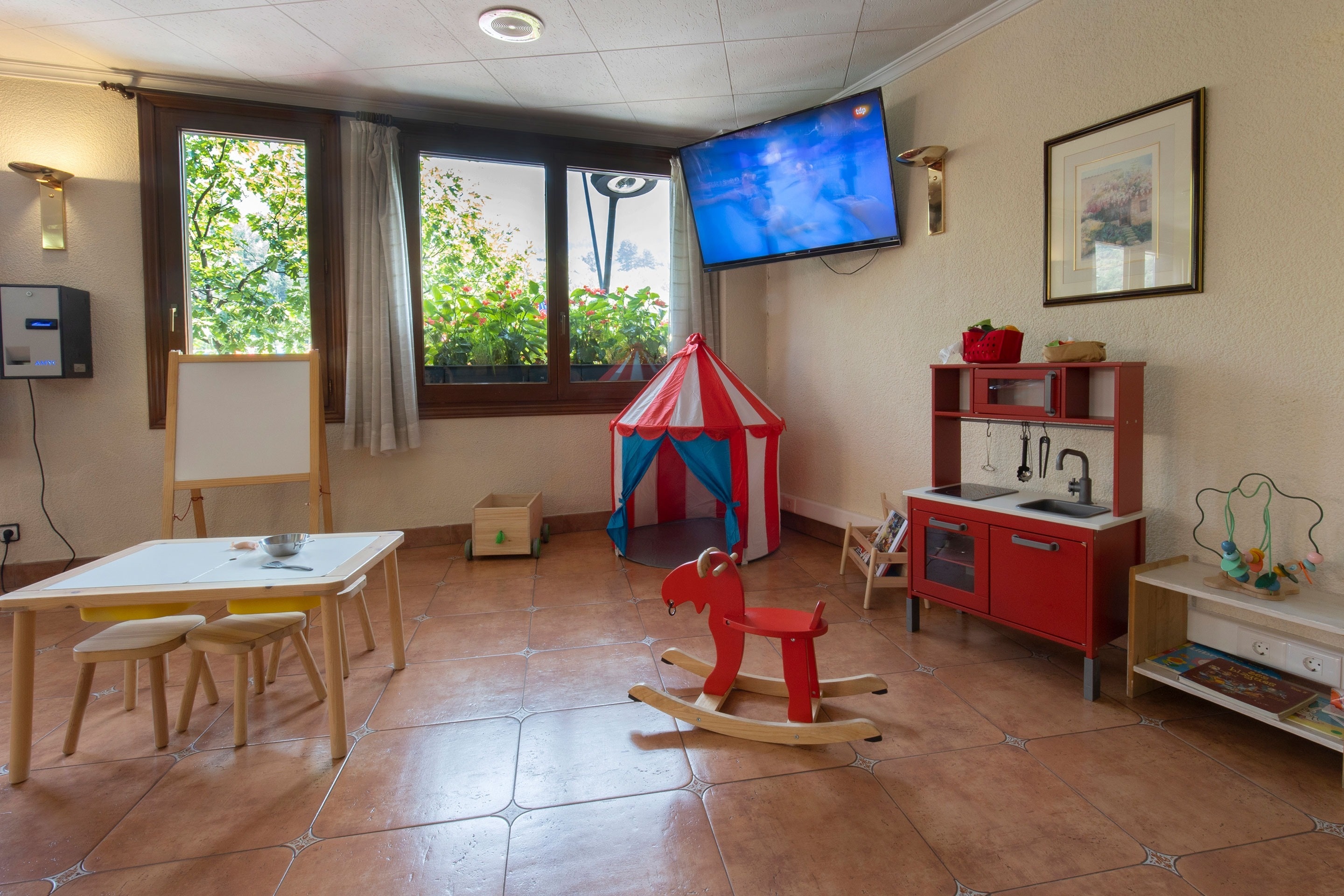 una sala de juegos para niños con una tienda de circo y una televisión