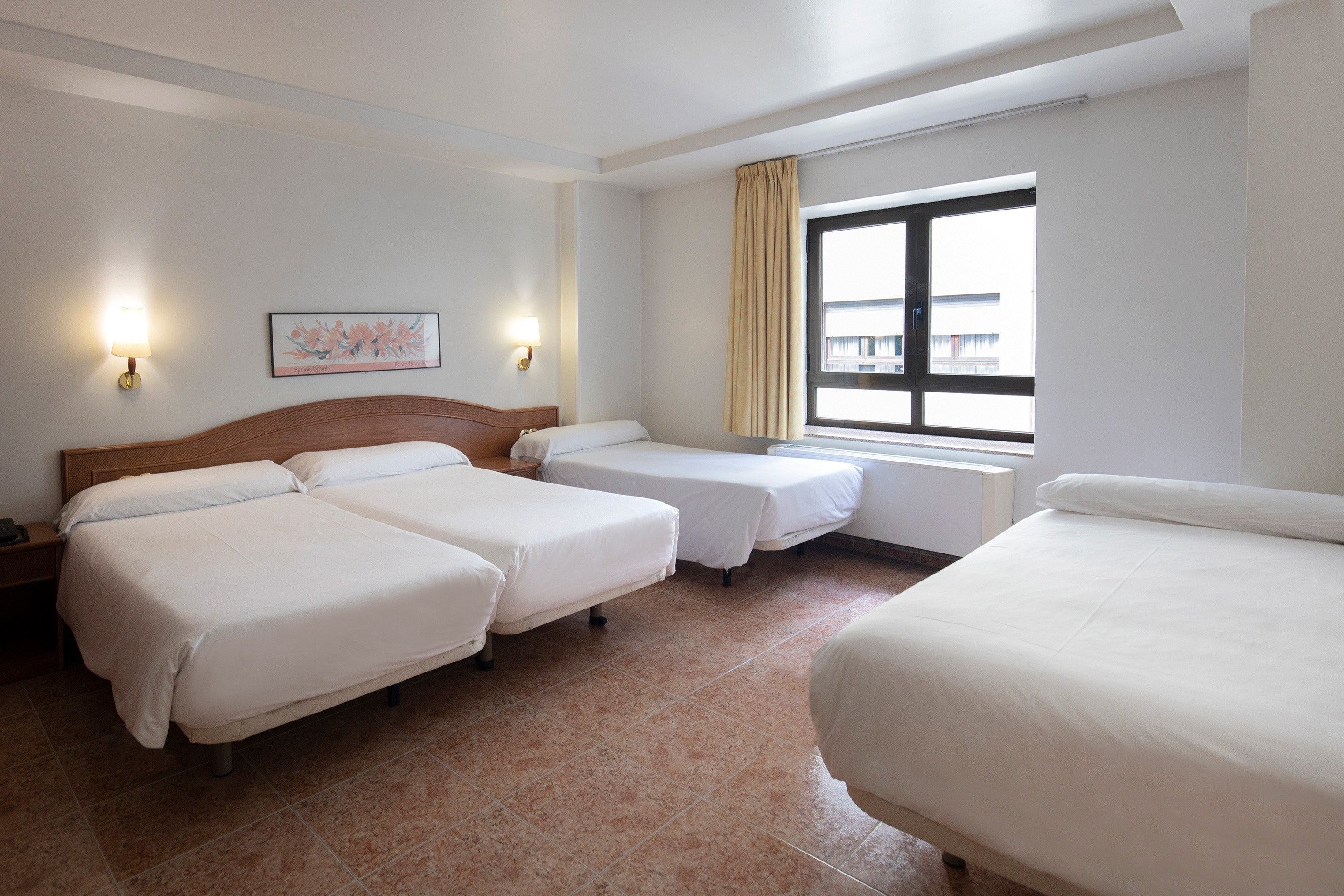 a hotel room with three beds and a window