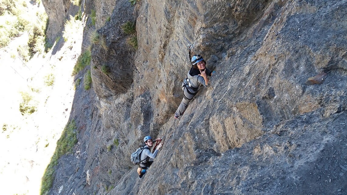 dos personas escalando una pared de roca con cascos de petzl