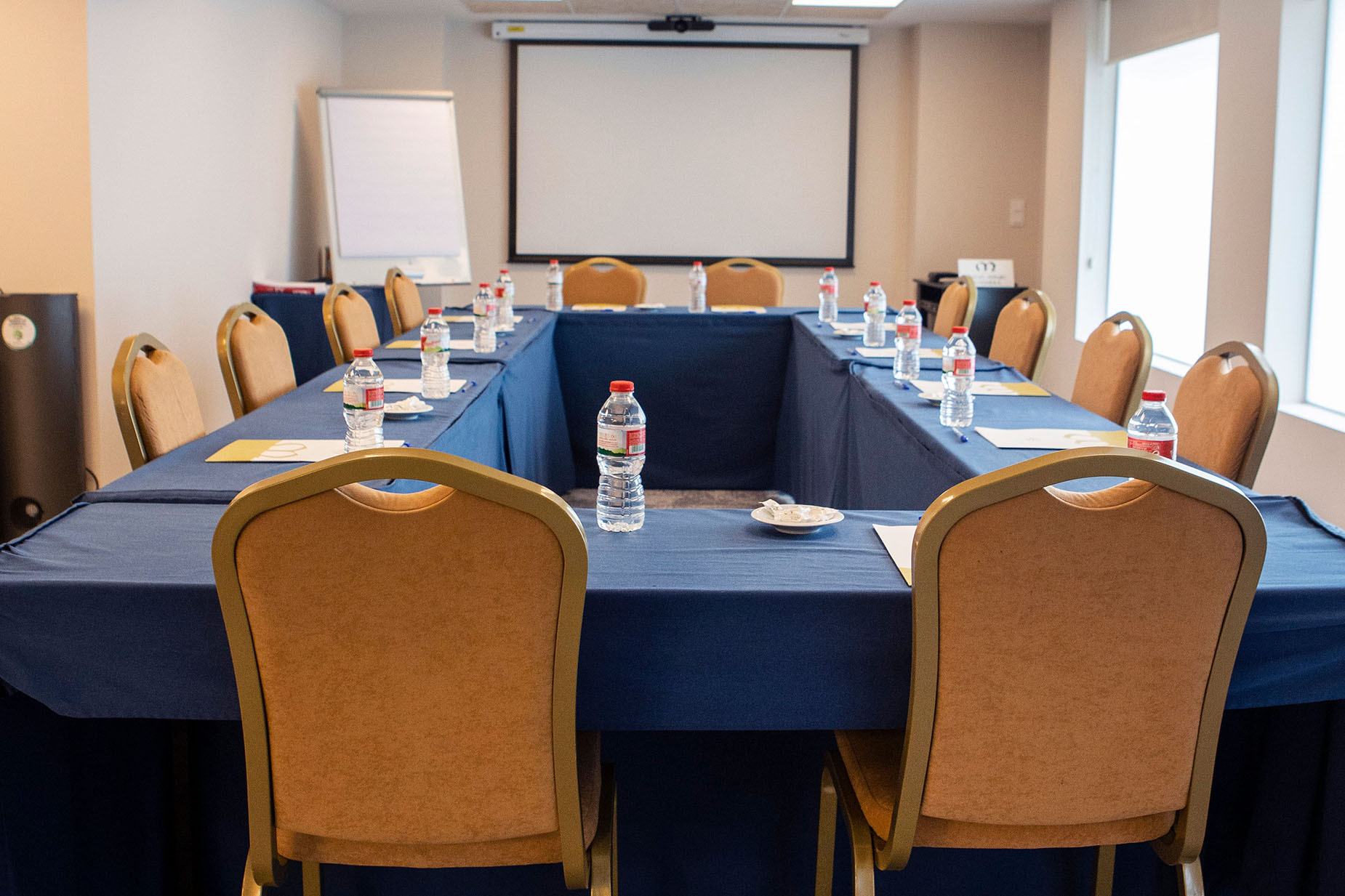 Sales meeting setup withNEXTA: Corporativarental tables, chairs, and projector screen.