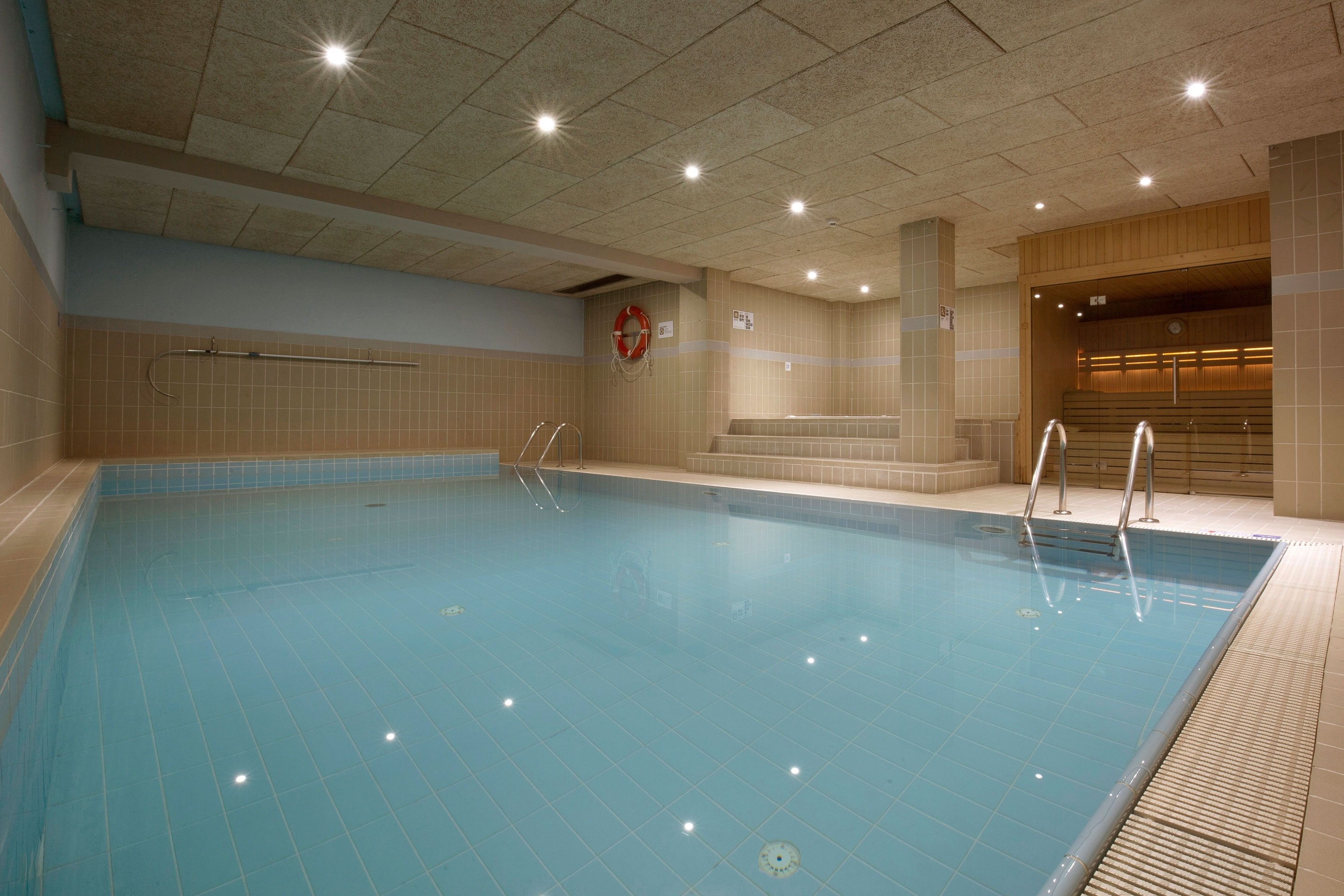 una piscina interior amb escales i un flotador