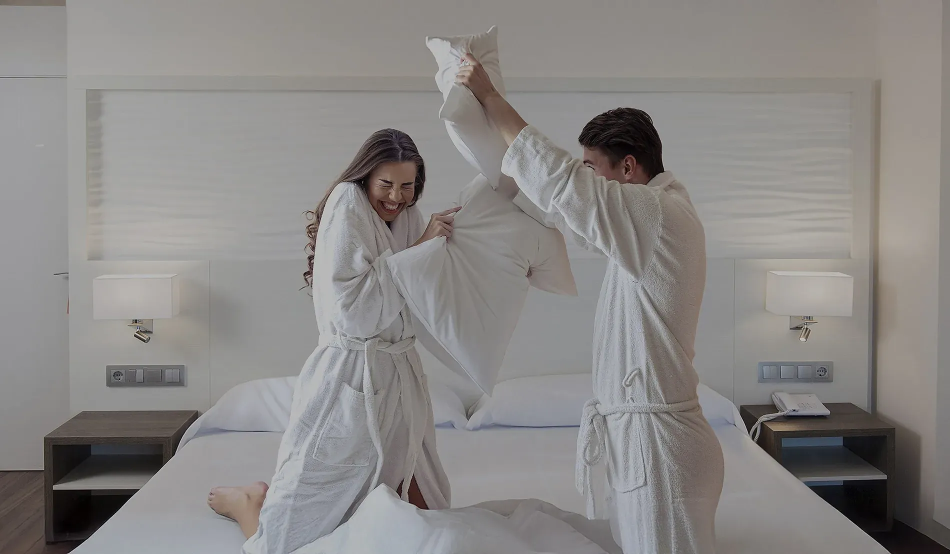 Couple riant au lit en peignoirs, expérience NEXTA: Corporativa.