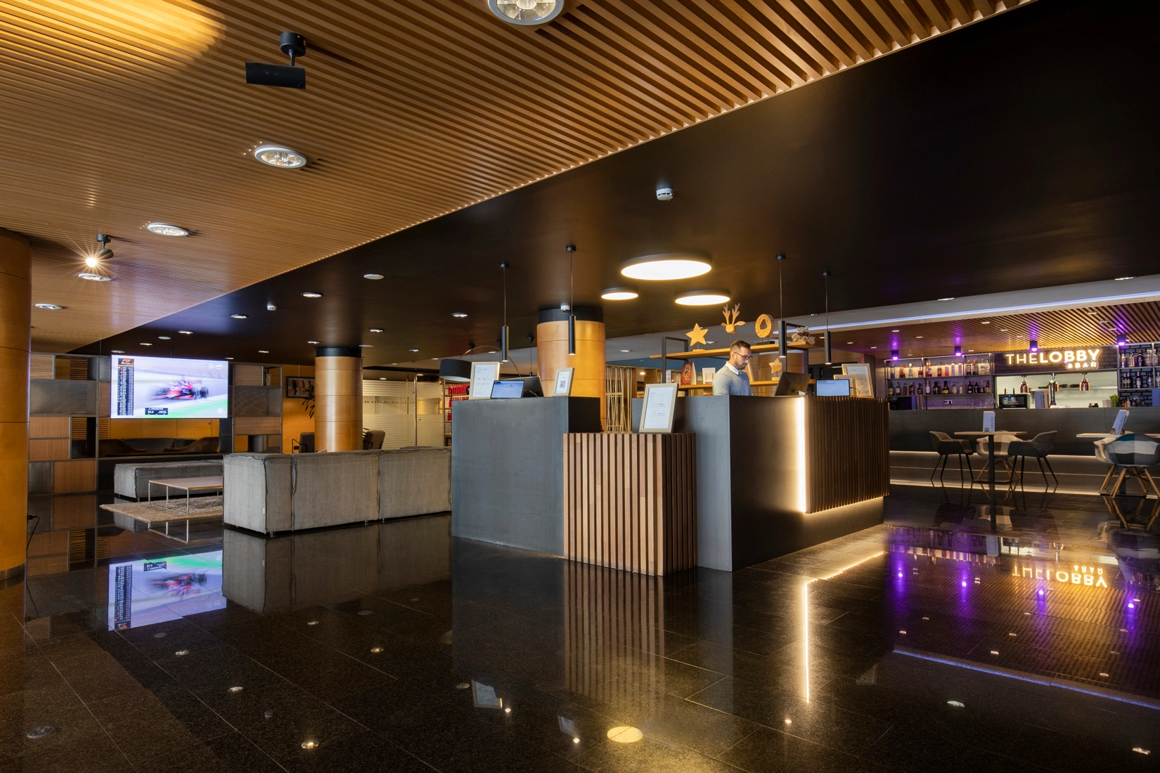 Hotel Nexta: chimenea moderna, sofás grises y mesa de centro de madera.