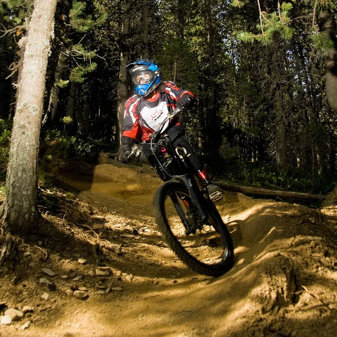 Ciclista de muntanya baixant un camí boscat, ideal per NEXTA: Corporativa.