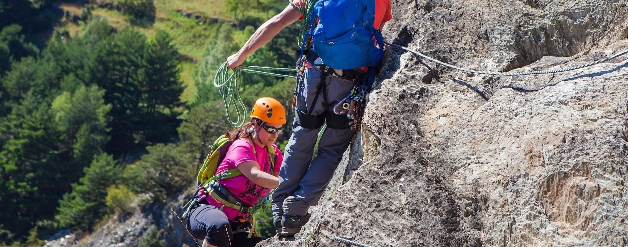 un hombre ayuda a una mujer a escalar una montaña