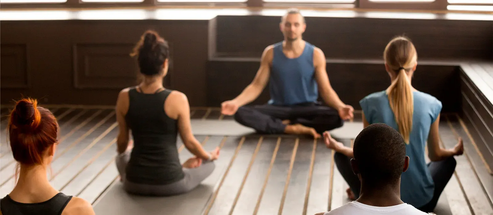 NEXTA: Corporativa yoga class, instructor leading meditation in lotus pose.